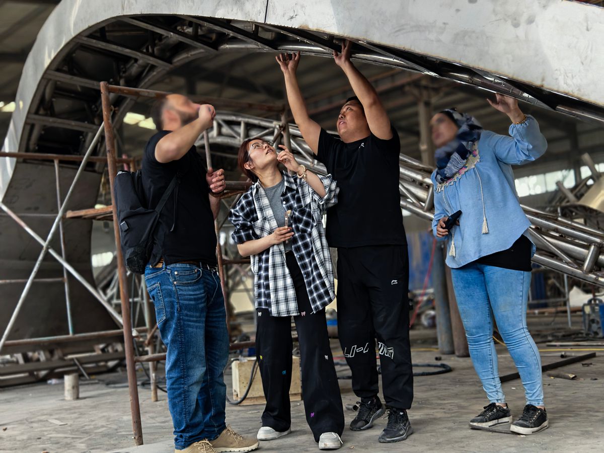 Client representatives inspecting the stainless steel sculpture at the factory